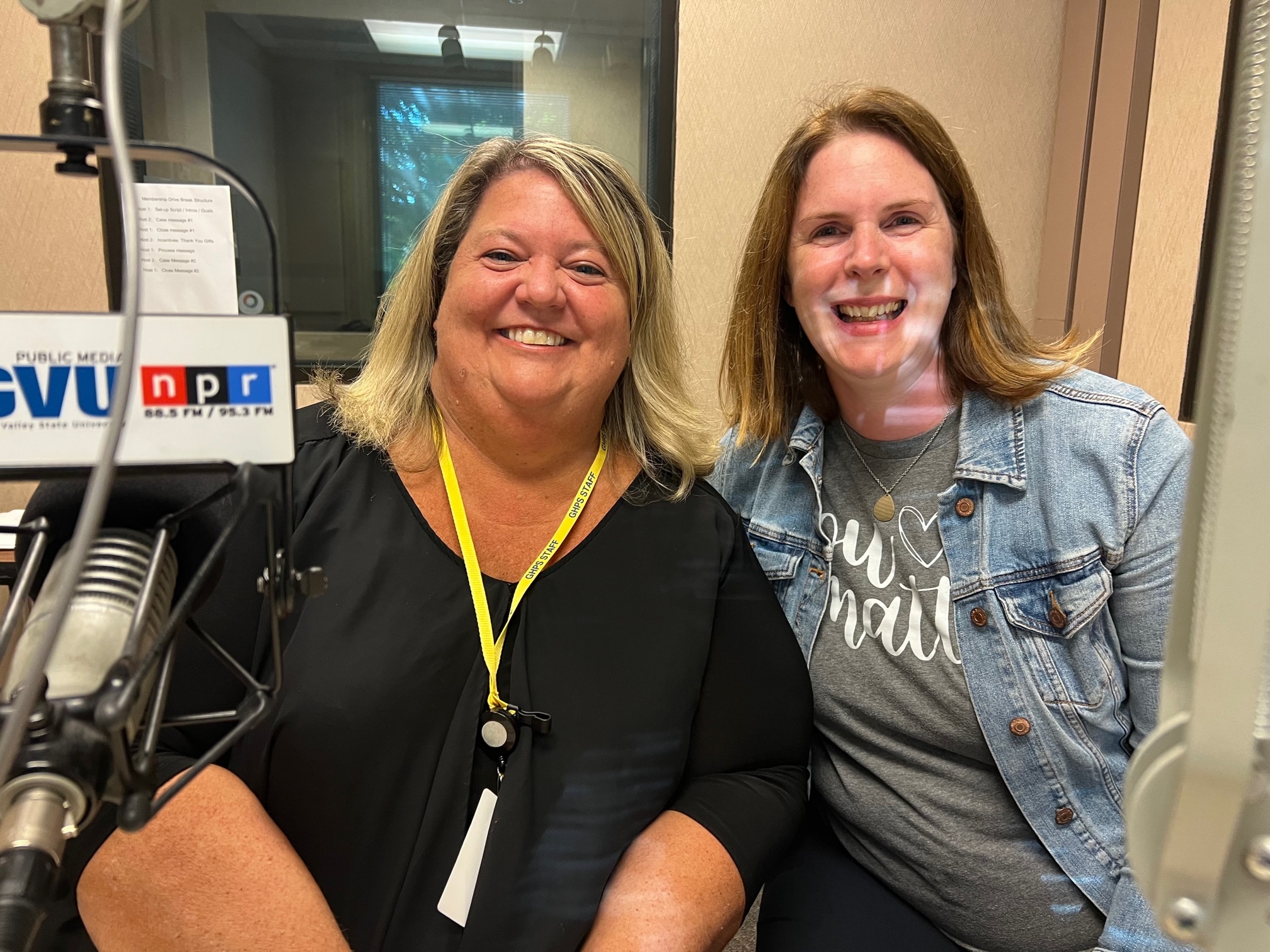 Two ladies sit in front of microphone at radio station
